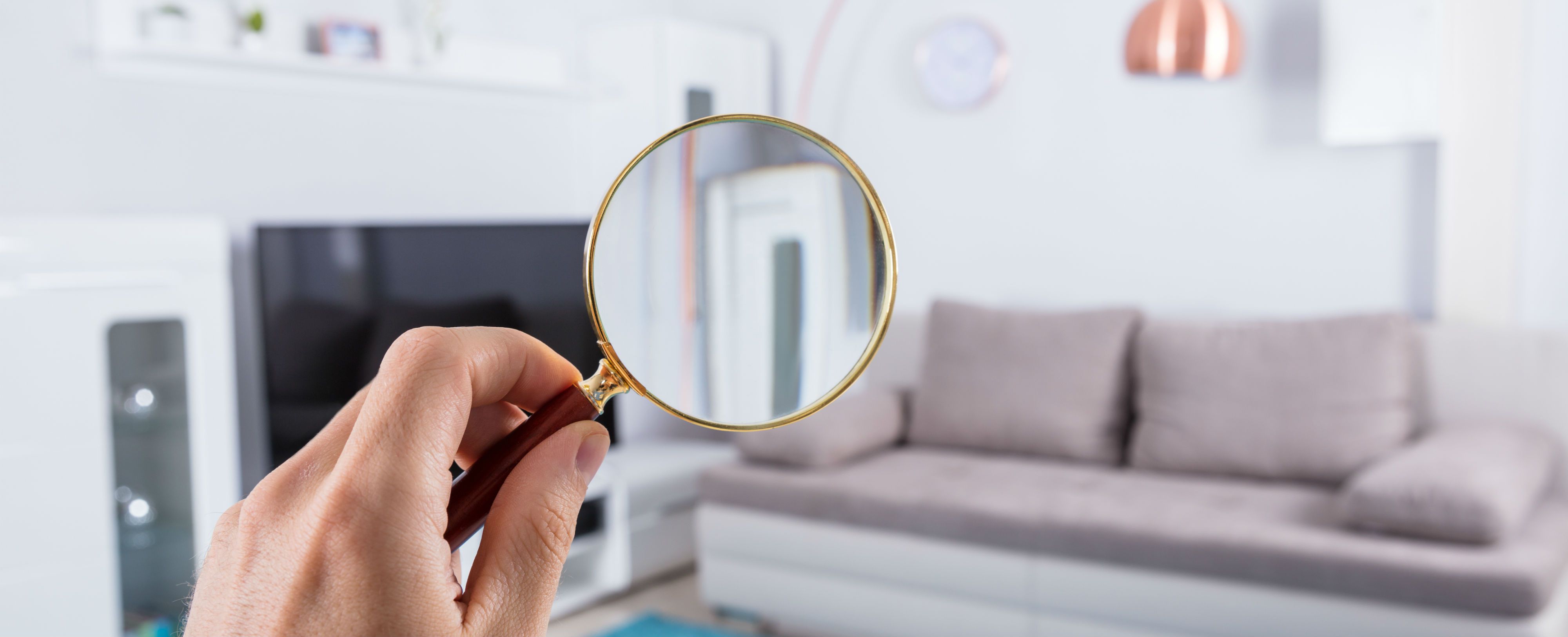 An oversized magnifying glass inspects a room in a house.